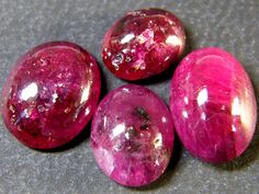 three pink stones sitting next to each other on a gray surface with white speckles