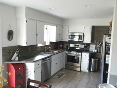 a kitchen with white cabinets and stainless steel appliances, including a dishwasher, stove, sink, microwave, refrigerator and dining room table