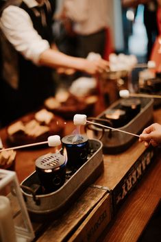 two people preparing food at a buffet table with utensils in the foreground