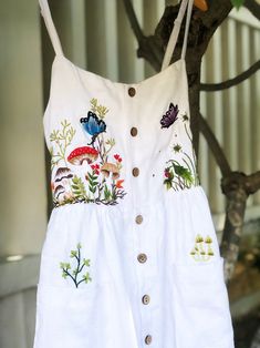 You love mushroom? Me too. I was filled of joy when I emberoidered this dress.   ❤ It's a lovely dress like a mini forest with colourful embroidered mushroom, flowers, strawberry, butterfly and bee motifs. - Material: linen, coconut button, hand embroidery. - Environmentally friendly. - This dress is very useful, go with any outfit, that can be used to go to school, go out, go shopping.    It is a perfect gift for yourself or your beloved.  ❤ Care instructions:      The best way to wash embroidery cloth is to put it in soapy water (with a mild detergent and cold water at 86 ºF/30oС) for 20 minutes. Try to not wash the item with other clothing that might cause damage, such as zippers, buttons or different colors. You wash it by hand, and if you have dirty patches on your garment, you can ge Embroidered Dress Diy, Strawberry Butterfly, Dress Hand Embroidery, Mini Forest, Simple Frocks, Hand Embroidery Dress, Go To School, Embroidery Motifs, Embroidered Clothes