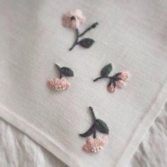 some pink flowers are on top of a white linen material that has been stitched together