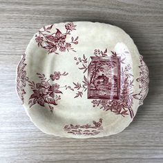 a red and white plate sitting on top of a wooden table next to a wall