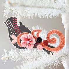 an ornament hanging from a christmas tree with pink and black flowers on it