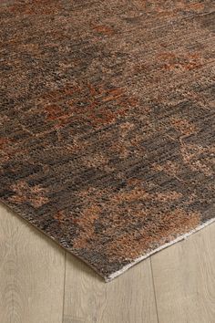 a brown and black rug on the floor with wood floors in the background, close up