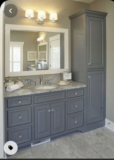 a bathroom with gray cabinets and marble counter tops