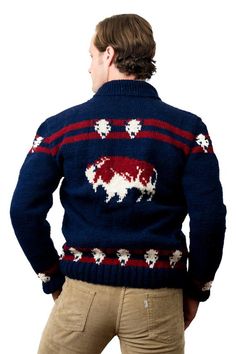 a man wearing a sweater with sheeps on it, back to the camera and his hands in his pockets