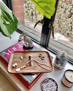 a wooden tray sitting on top of a window sill next to a candle and other items