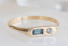 a close up of a ring on a white surface with a blue stone in the middle