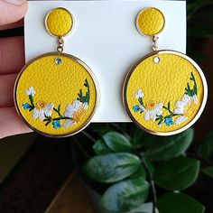 a pair of earrings with daisies painted on them