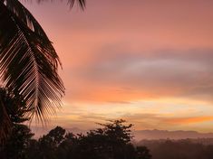 the sky is pink and orange as the sun sets in the distance with mountains in the background