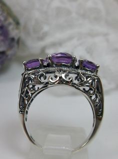 Natural Amethyst Ring 3Stone Design#36 Custom Made Inspired by Edwardian era designs, I now offer this exquisite reproduction ring in sterling silver. The full-cut natural amethyst in the center is 10mm (8/8th of an inch long), the 2 on the side are 8mm (5/16th of an inch long). The 3 stones together, east-west on the finger, are 20mm (13/16th of an inch) across. These flawless gemstones have perfect color and clarity. The band is hallmarked 925 for sterling. A ring gift-box is included. Feel fr Formal Three Stone Amethyst Ring, Three Stone Amethyst Ring, Classic Three Stone Purple Jewelry, Three Stone Amethyst Ring As A Gift, Anniversary Three Stone Amethyst Ring, Oval Purple Amethyst Ring With Stone Setting, Amethyst Three Stone Ring, Three Stone Amethyst Jewelry, Silver Amethyst Ring With Intricate Design