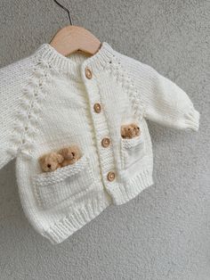 a white sweater with two teddy bears in it hanging on a clothesline next to a wall