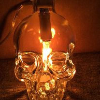 a glass skull lamp is lit up in the dark with its head turned upside down