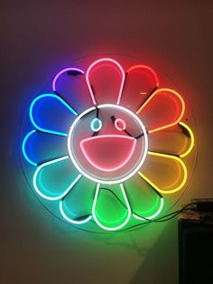 a colorful neon sign with a smiley face on it's back wall hanging from the ceiling