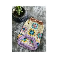 a crocheted pot holder sitting on top of a gray rug next to a plant