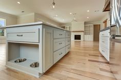 an empty kitchen with wooden floors and white cabinets