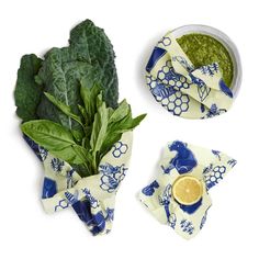 spinach leaves and other vegetables are on plates with napkins, cups and saucers