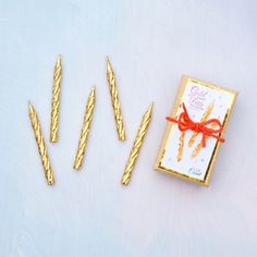 three gold colored nails with a red bow tied around them and two small ones next to each other on a white surface