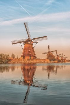 the windmills are reflected in the still water