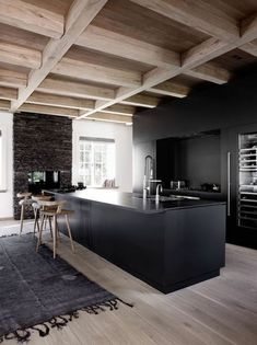 a large kitchen with an island in the middle and wooden beams on the ceiling above it