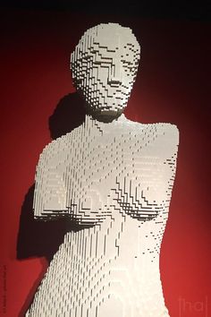 a sculpture made out of white legos on a red background with the shadow of a woman's torso