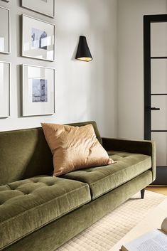 a living room with a green couch and some pictures on the wall above it,