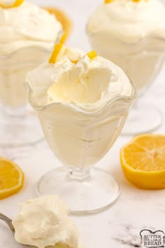 three desserts with lemon and whipped cream in glass dishes on a marble countertop