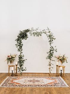 a wedding arch decorated with greenery and white flowers sits in front of two chairs