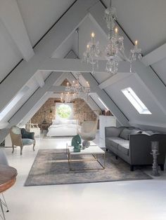 an attic living room with couches and chandelier