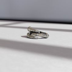 two silver rings sitting on top of a white table next to each other with shadows