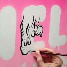 a person is painting the letters on a pink wall with black and white inks