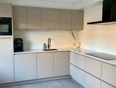 an empty kitchen with white cabinets and black appliances on the counter top, in front of a microwave oven