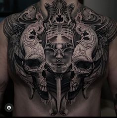 a man's back with tattoos on his chest and head in the middle, surrounded by skulls