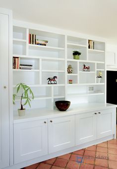 a living room filled with lots of white furniture and bookshelves next to a window