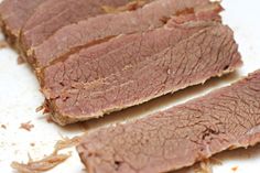 sliced meat sitting on top of a white cutting board