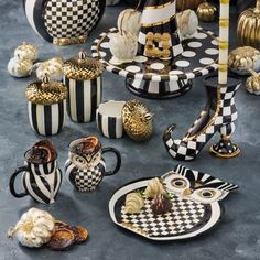 an assortment of black and white dishes with gold accents on them, sitting in front of pumpkins