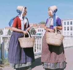 two women in long dresses carrying baskets on their backs