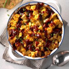 a casserole dish with meat and vegetables in it on a napkin next to a spoon