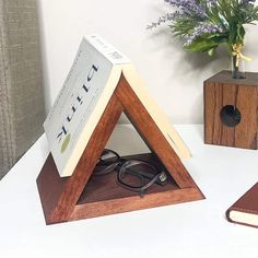 a wooden book stand with a pair of reading glasses on it and a notebook in front of it