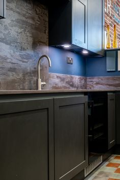 a kitchen with blue walls and black cupboards next to a brick wall in the background