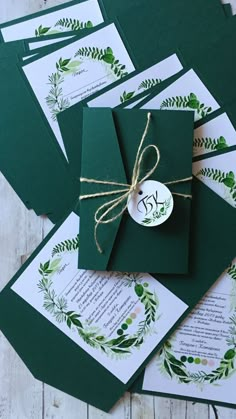 some green envelopes tied with twine on top of each other and decorated with greenery