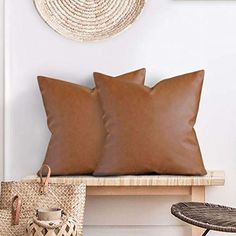 two brown pillows sitting on top of a wooden bench next to a wicker basket