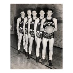 an old black and white photo of men in basketball uniforms standing next to each other