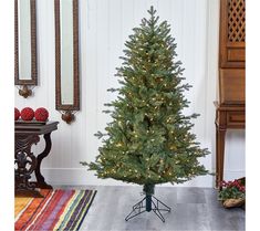 a small christmas tree in a living room next to a mirror and table with ornaments on it