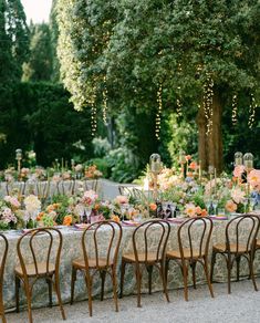 an outdoor dinner table set up with chairs and tables covered in floral centerpieces