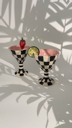 two black and white checkered cups with lime slices in them, one has a strawberry on top