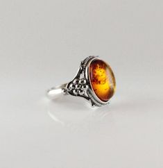 Ornated silver cognac color Amber ring with sterling silver oval shape Baltic amber jewelry cognac, ornated with vines genuine amber Classic antique style Amber ring Oval shape cabochon 925e sterling silver handmade sparkling cognac or dark green color  COLORS : the real stone color is more orange cognac then the picture Solid sterling bezel silver 925e handmade  Dimensions Stone size : 14 x 10 mm Length : 16.5 mm  Width : 18 mm  Height : 7.5 Weight : 4.7 gr Size of ring : 7.5 us,ca - 55, 56 France - P, P½ Uk sizing Classic Amber Oval Cabochon Jewelry, Classic Amber Ring Jewelry, Elegant Amber Cabochon Ring, Formal Amber Oval Cabochon Rings, Amber Cabochon Wedding Jewelry, Amber Cabochon Jewelry For Wedding, Classic Amber Sterling Silver Ring, Hallmarked Amber Oval Cabochon Jewelry, Oval Amber Cabochon Jewelry