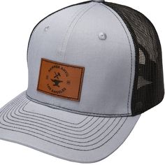 a gray and black trucker hat with an orange patch on the front that says,