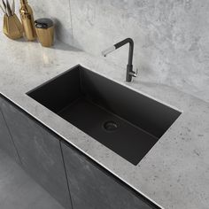 a black sink sitting on top of a counter next to a knife holder and utensils