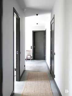 an empty hallway with black doors and chairs